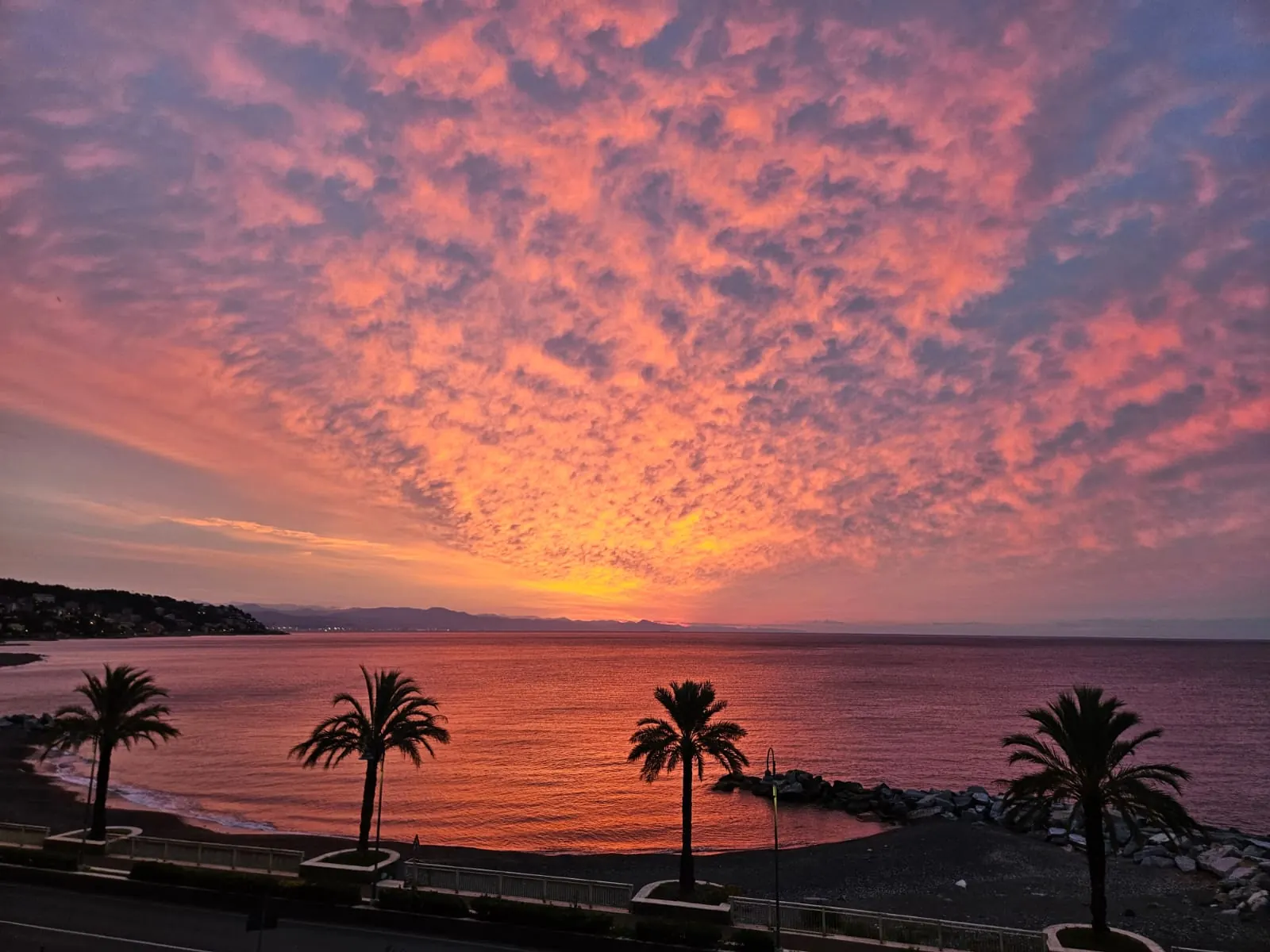 Cogoleto — vista del borgo dalla riva al tramonto, con i tetti del centro storico e il mare